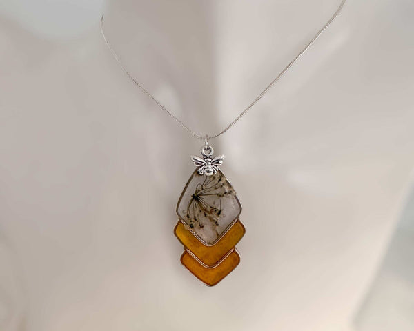Capture nature's beauty with this exquisite honey bee themed pendant, crafted with real pressed flowers encased in honey-tinted resin. Handmade and one of a kind