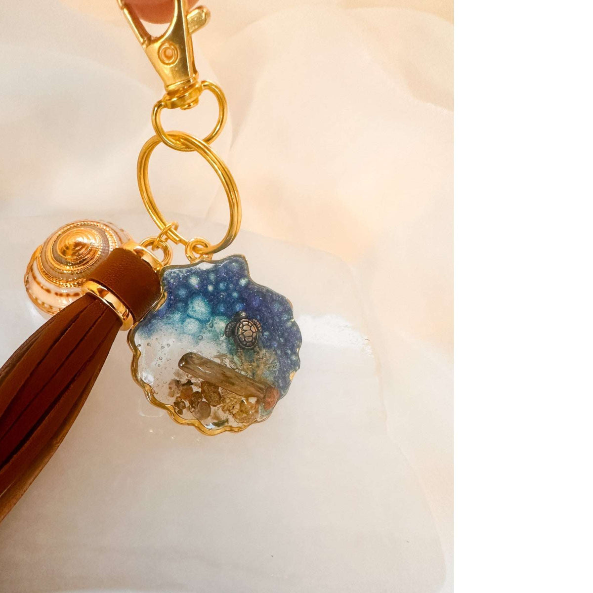 Handmade "Coastal Embrace" Keychain ($42): Real sand, seashells, & a silver turtle in glittering blue resin. Unique, luxury leather tassel & gold charm.