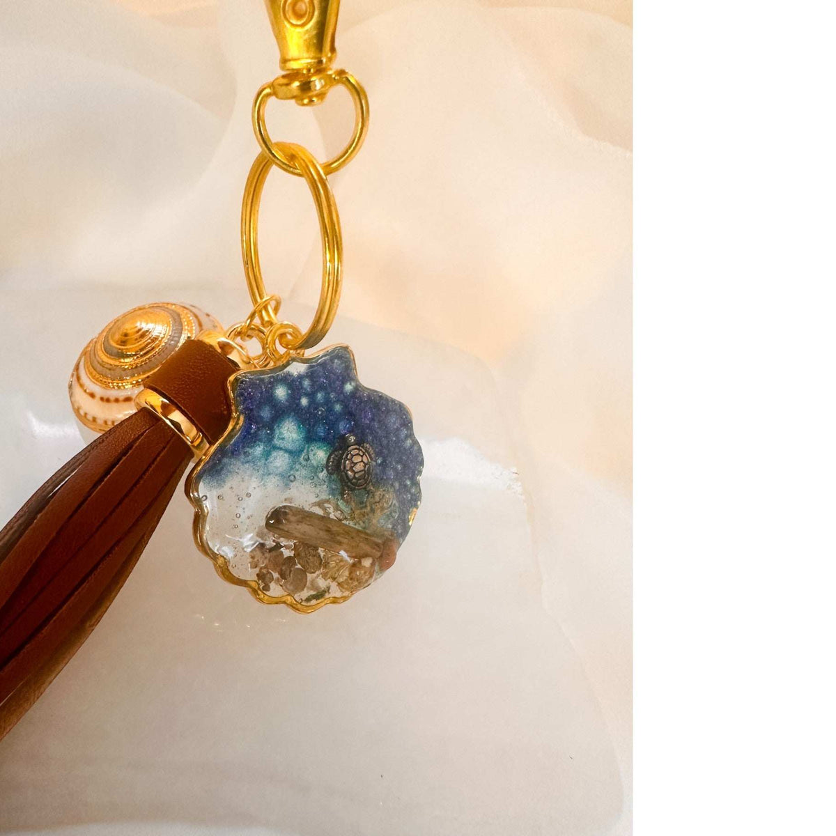 Handmade "Coastal Embrace" Keychain ($42): Real sand, seashells, & a silver turtle in glittering blue resin. Unique, luxury leather tassel & gold charm.