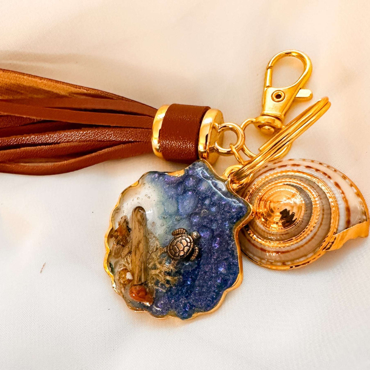 Handmade "Coastal Embrace" Keychain ($42): Real sand, seashells, & a silver turtle in glittering blue resin. Unique, luxury leather tassel & gold charm.