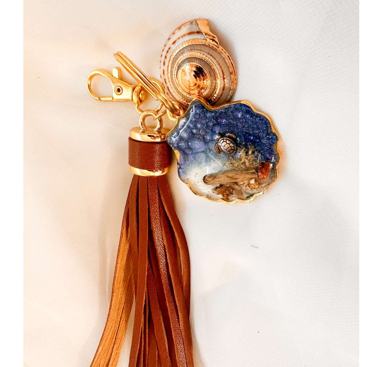 Handmade "Coastal Embrace" Keychain ($42): Real sand, seashells, & a silver turtle in glittering blue resin. Unique, luxury leather tassel & gold charm.