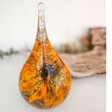 A teardrop-shaped resin ring holder containing a real Black-Eyed Susan and sunflower with gold leaf accents on a wooden surface.