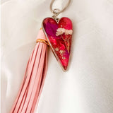 Antique silver heart bag charm filled with pink and purple resin and real white flowers, attached to a pink leather tassel