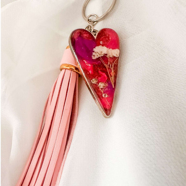 Antique silver heart bag charm filled with pink and purple resin and real white flowers, attached to a pink leather tassel