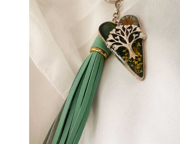 Secret Garden Bag Charm & Silver Tree of Life heart charm with a moss green resin background, real yellow flowers, and a tiny daisy, featuring a green leather tassel.