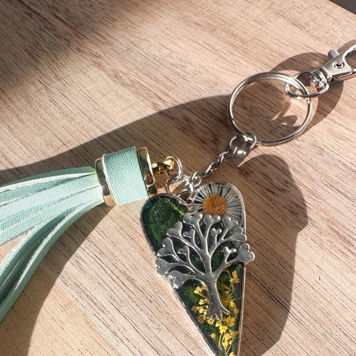 Secret Garden Bag Charm & Silver Tree of Life heart charm with a moss green resin background, real yellow flowers, and a tiny daisy, featuring a green leather tassel.