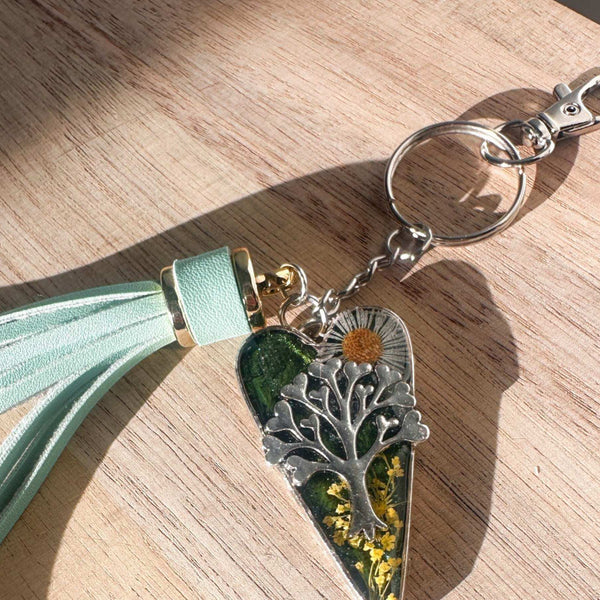 Secret Garden Bag Charm & Silver Tree of Life heart charm with a moss green resin background, real yellow flowers, and a tiny daisy, featuring a green leather tassel.