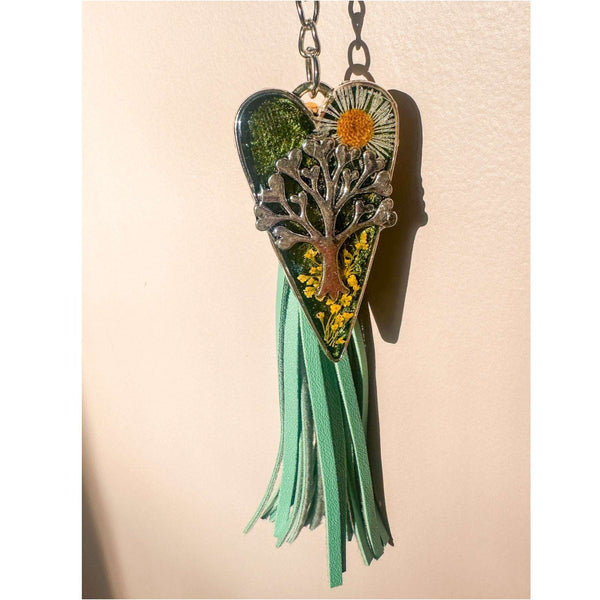 Secret Garden Bag Charm & Silver Tree of Life heart charm with a moss green resin background, real yellow flowers, and a tiny daisy, featuring a green leather tassel.
