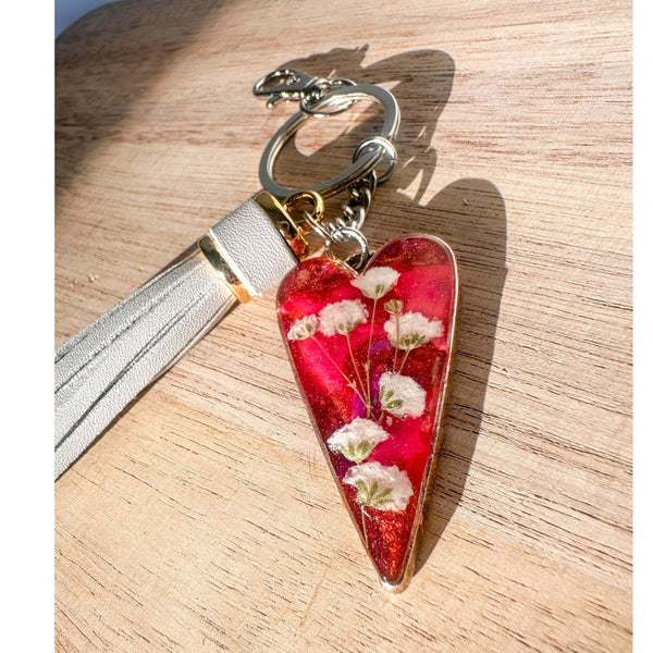 Antique silver heart bag charm filled with pink and purple resin and real white flowers, attached to a gray leather tassel