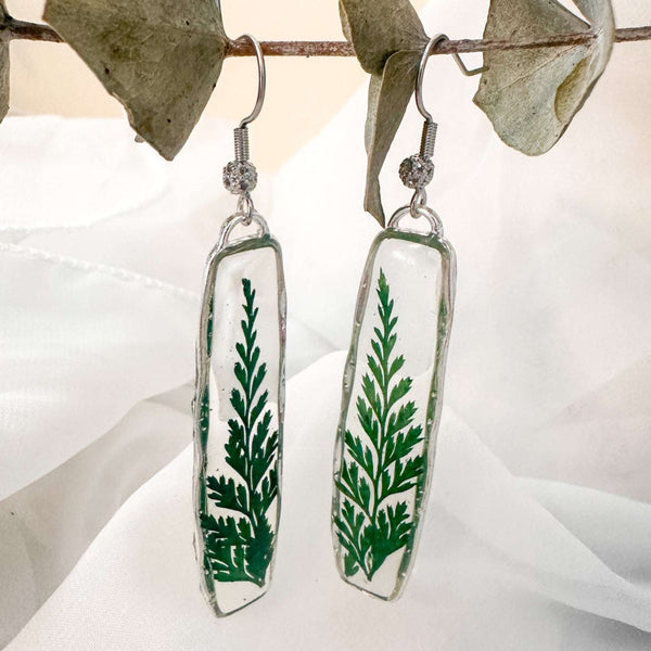 Close-up of the natural sculpted edges of these minimalist boho fern drop earrings in silver.