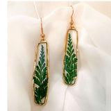 Handcrafted Fern's Embrace drop earrings featuring real green fern fronds in a clear resin setting.