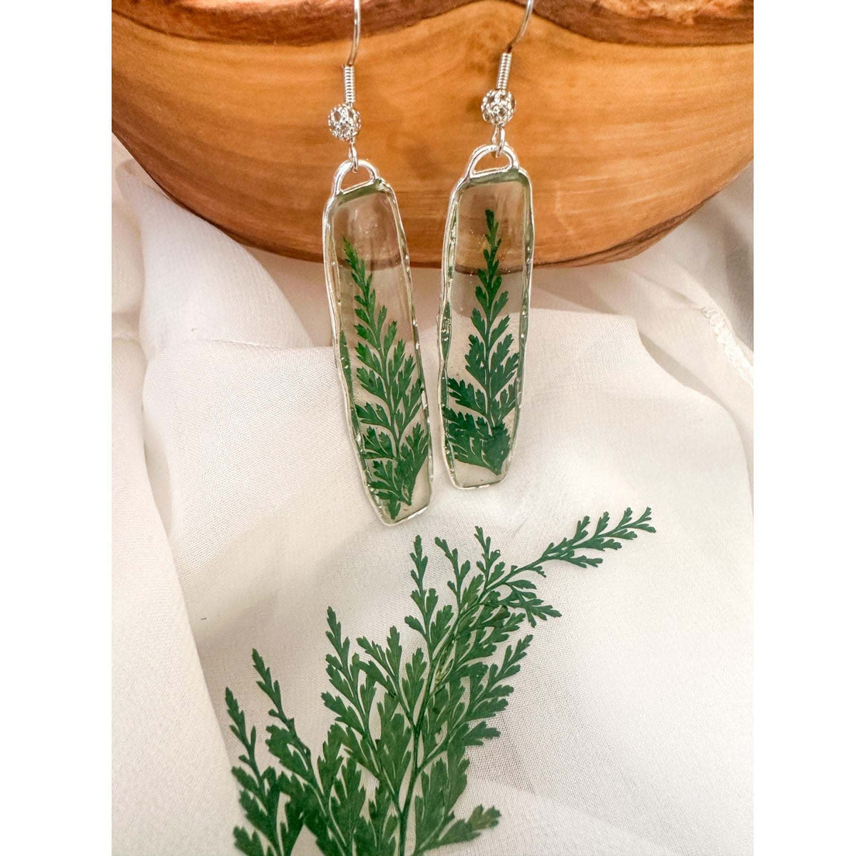 Handcrafted Fern's Embrace drop earrings featuring real green fern fronds in a clear resin setting.
