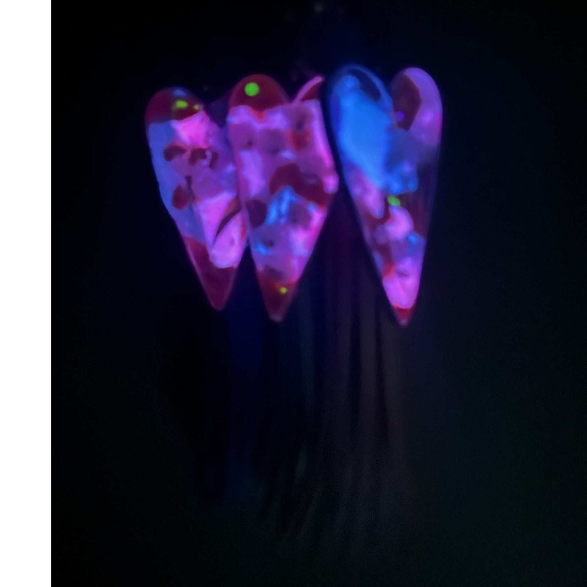 Close up of real white pressed flowers encased in vibrant pink and purple tinted resin inside a silver heart frame with glow in the dark feature