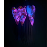 Close up of real white pressed flowers encased in vibrant pink and purple tinted resin inside a silver heart frame with glow in the dark feature