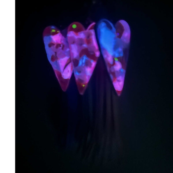 Close up of real white pressed flowers encased in vibrant pink and purple tinted resin inside a silver heart frame with glow in the dark feature