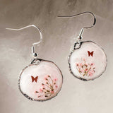 Close up of dark pink Queen Anne's Lace and a tiny floating butterfly inside pink floral butterfly earrings.