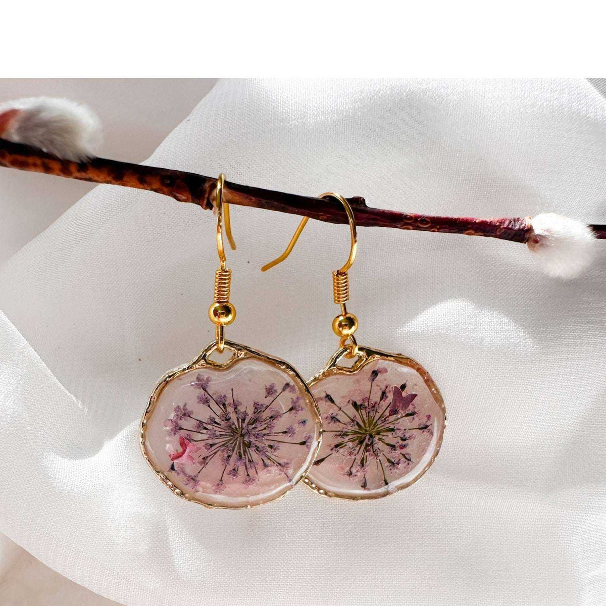 Close up of dark pink Queen Anne's Lace and a tiny floating butterfly inside pink floral butterfly earrings.