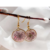 Close up of dark pink Queen Anne's Lace and a tiny floating butterfly inside pink floral butterfly earrings.
