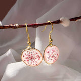 Close up of dark pink Queen Anne's Lace and a tiny floating butterfly inside pink floral butterfly earrings.