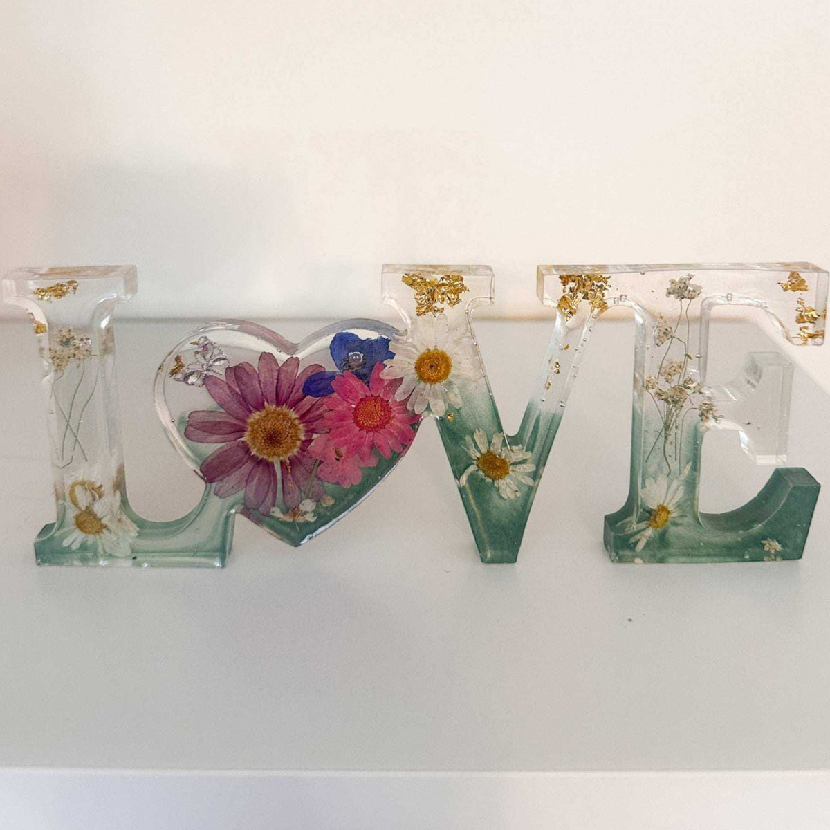 Handcrafted floral resin LOVE sign with a large pink cosmo and forest green base.