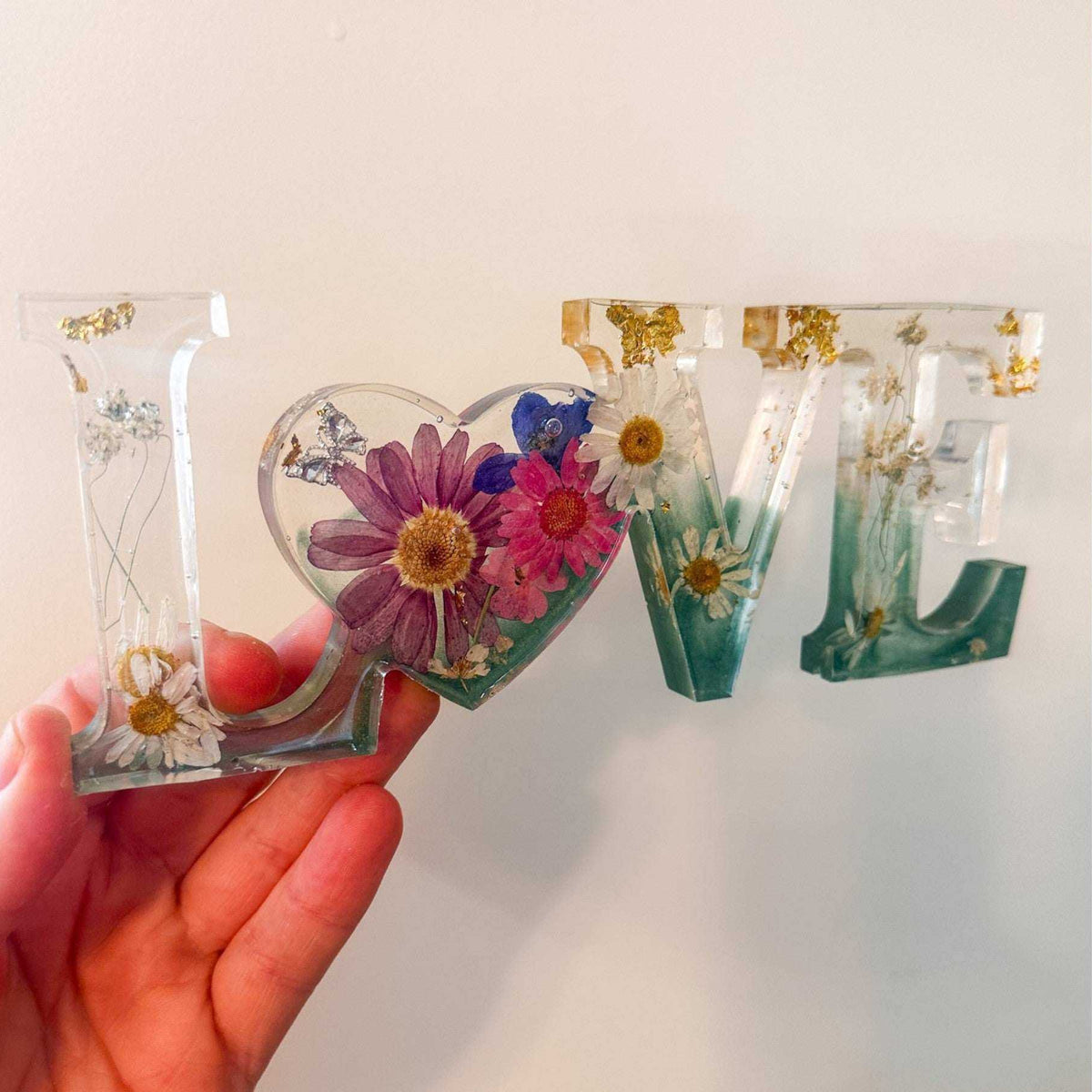 Handcrafted floral resin LOVE sign with a large pink cosmo and forest green base.