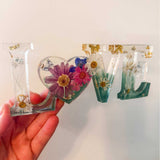 Handcrafted floral resin LOVE sign with a large pink cosmo and forest green base.