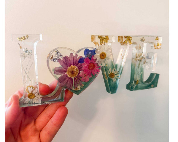 Handcrafted floral resin LOVE sign with a large pink cosmo and forest green base.