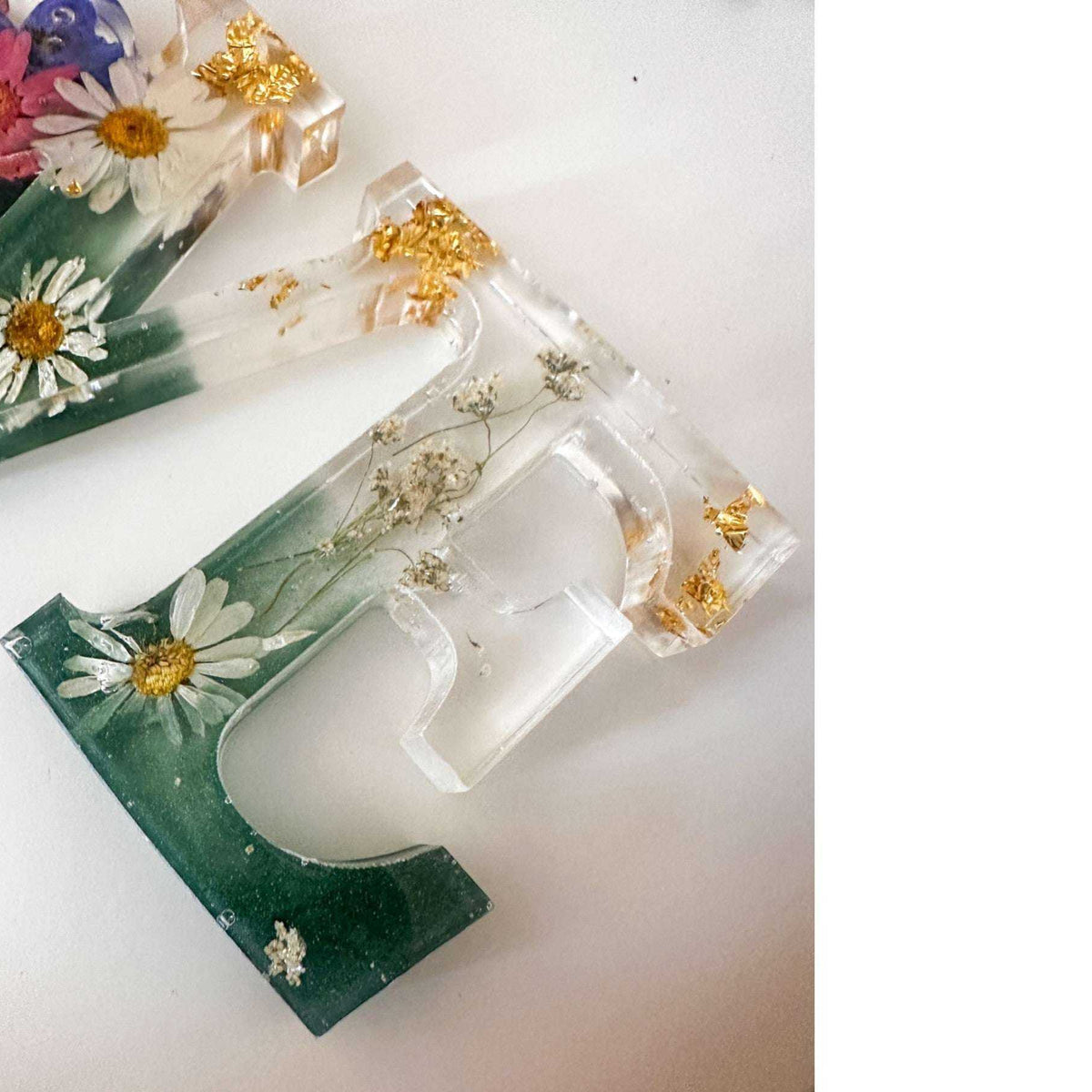 Close-up of real pink daisies and white floral accents inside a love word