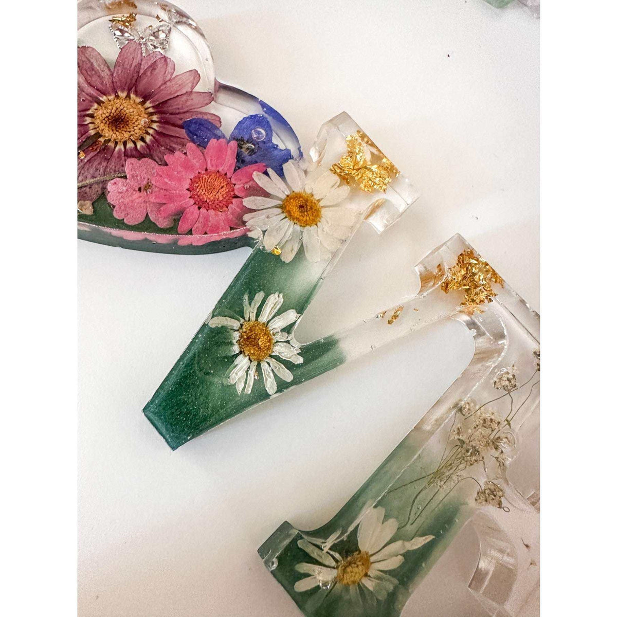 Close-up of real pink daisies and white floral accents inside a love word