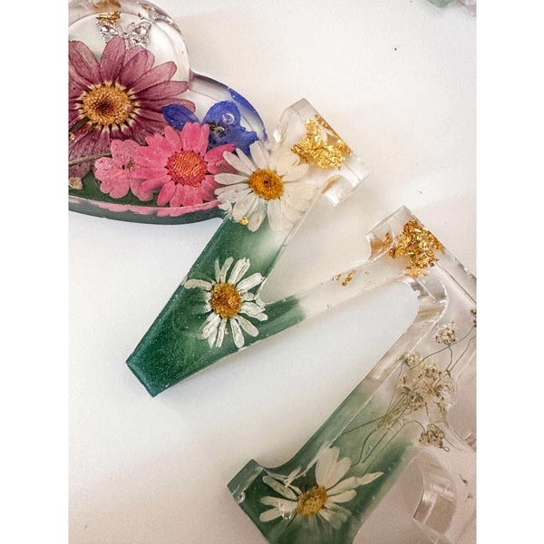 Close-up of real pink daisies and white floral accents inside a love word