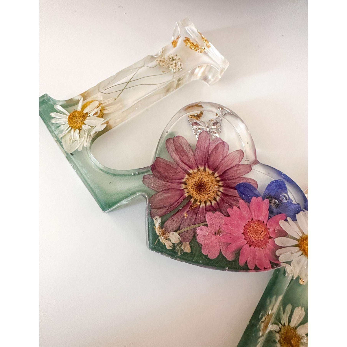 Close-up of real pink daisies and white floral accents inside a love word