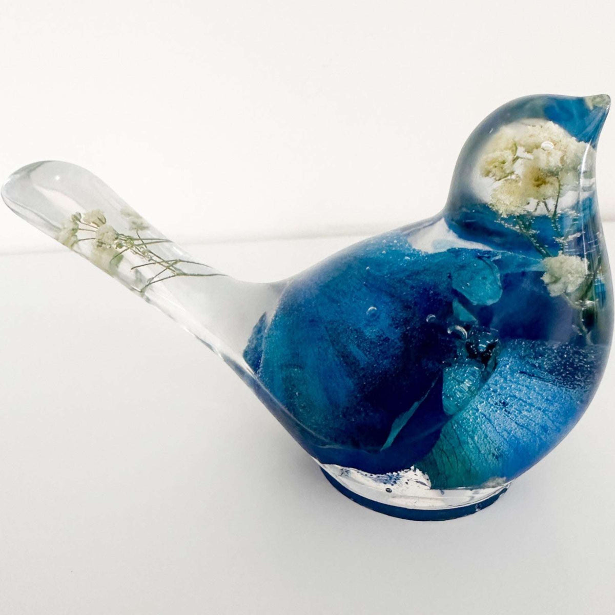 Close up of real blue rose petals and white baby's breath inside a Blue Rose Resin Bird.