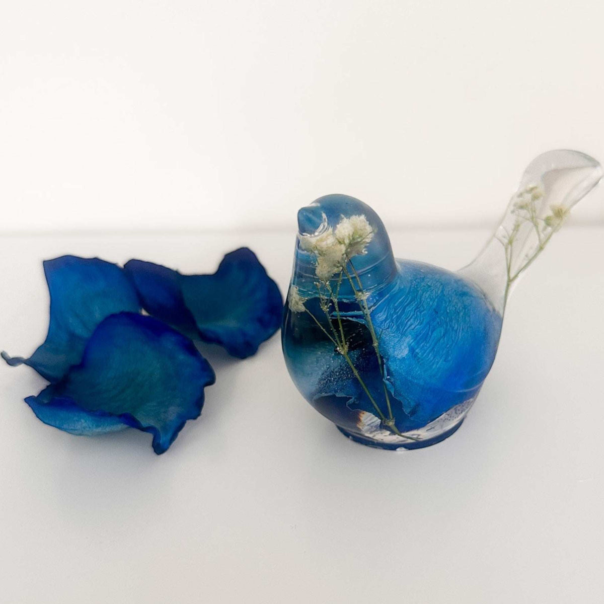 Close up of real blue rose petals and white baby's breath inside a Blue Rose Resin Bird.