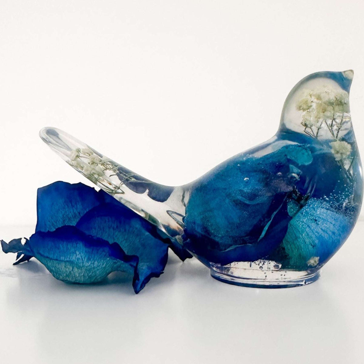 Close up of real blue rose petals and white baby's breath inside a Blue Rose Resin Bird.