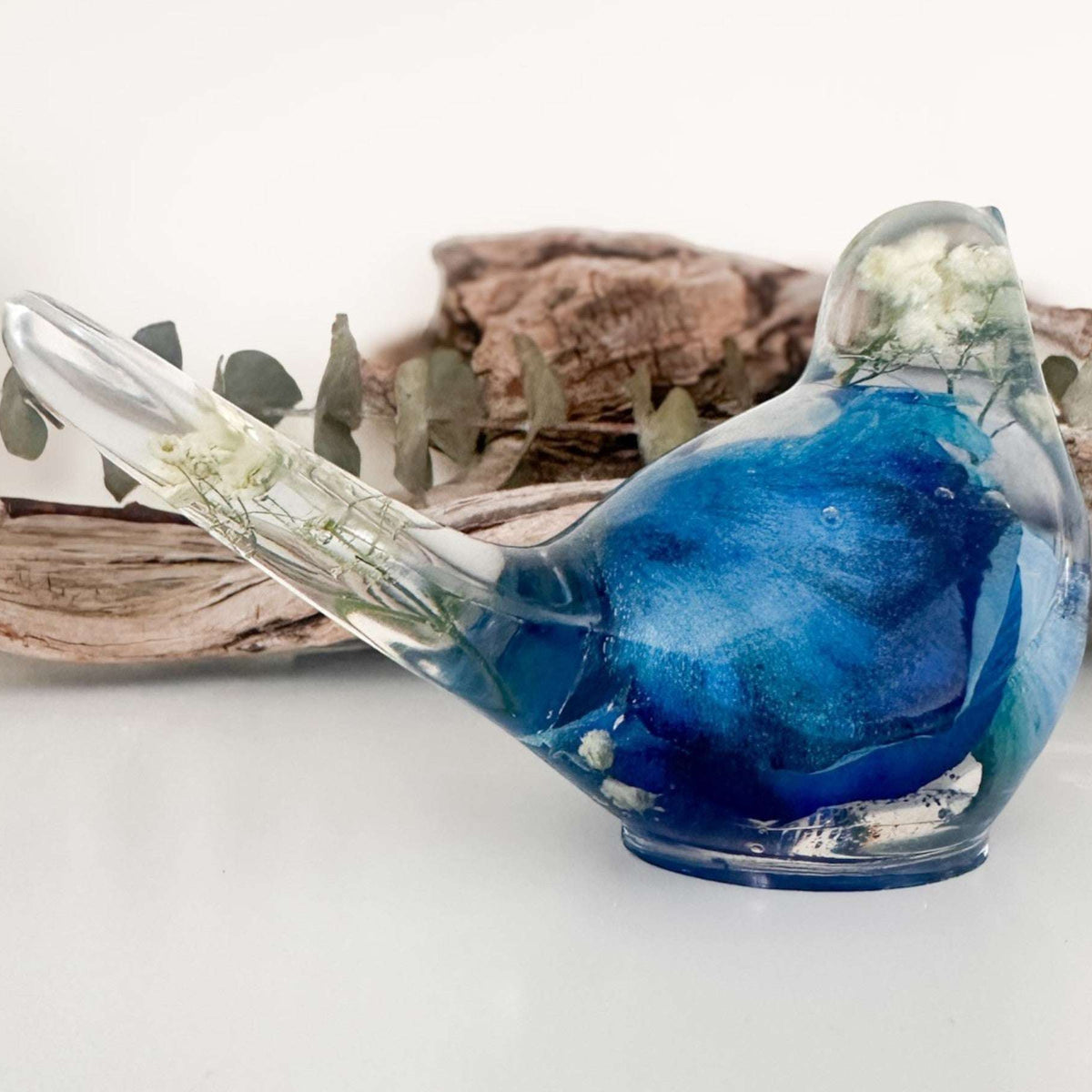 Close up of real blue rose petals and white baby's breath inside a Blue Rose Resin Bird.