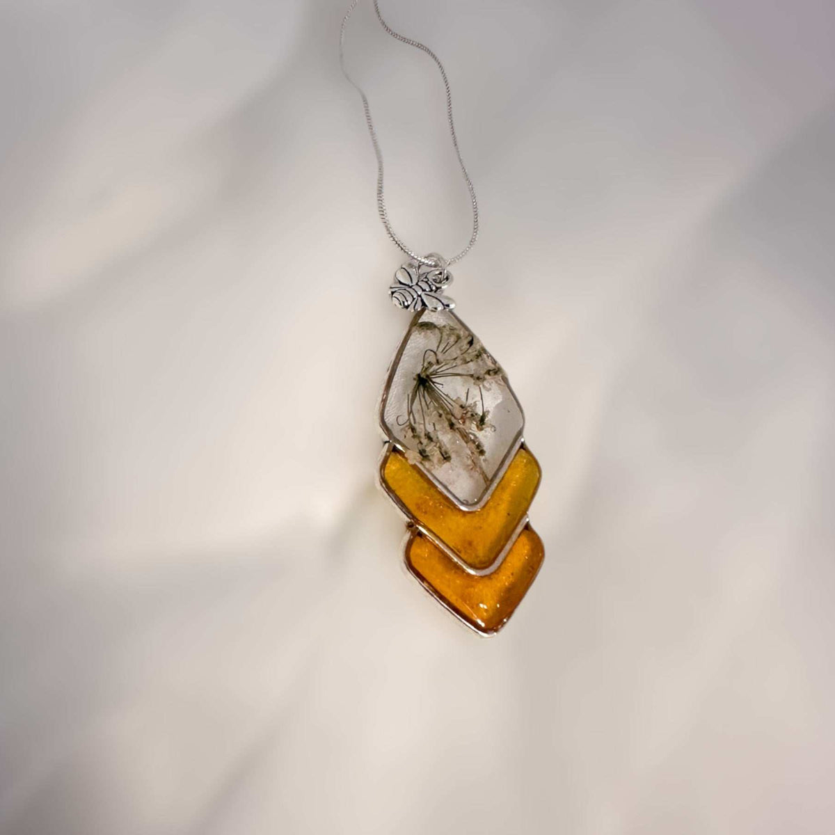 Capture nature's beauty with this exquisite honey bee themed pendant, crafted with real pressed flowers encased in honey-tinted resin. Handmade and one of a kind