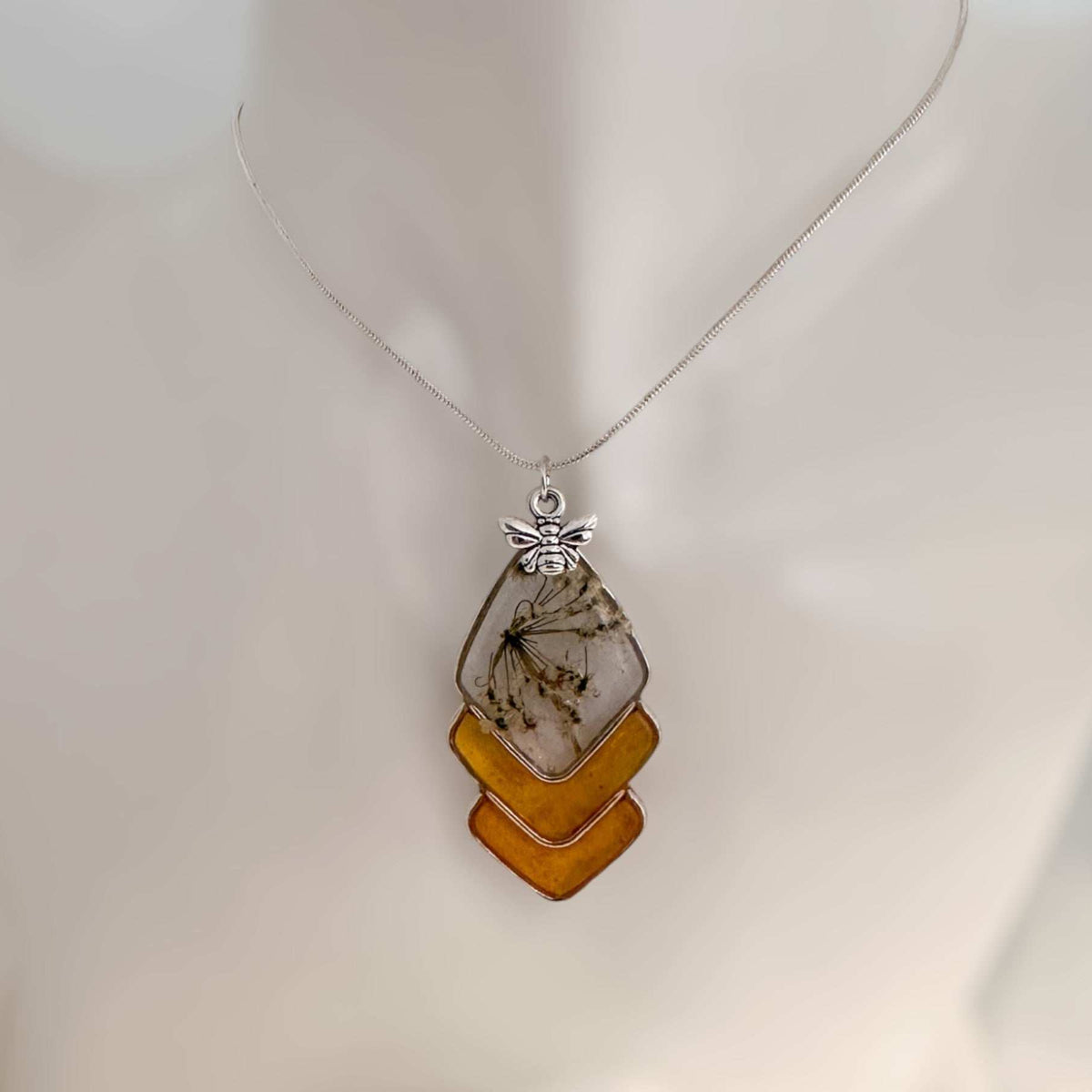 Capture nature's beauty with this exquisite honey bee themed pendant, crafted with real pressed flowers encased in honey-tinted resin. Handmade and one of a kind