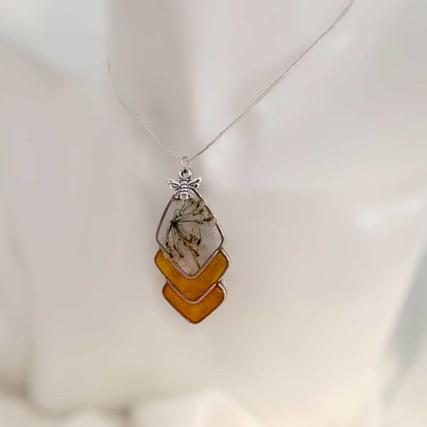 Capture nature's beauty with this exquisite honey bee themed pendant, crafted with real pressed flowers encased in honey-tinted resin. Handmade and one of a kind