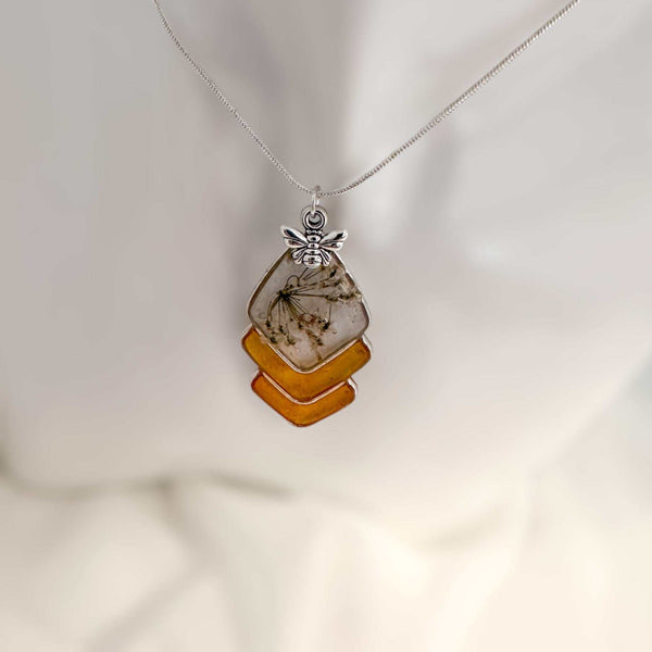 Capture nature's beauty with this exquisite honey bee themed pendant, crafted with real pressed flowers encased in honey-tinted resin. Handmade and one of a kind