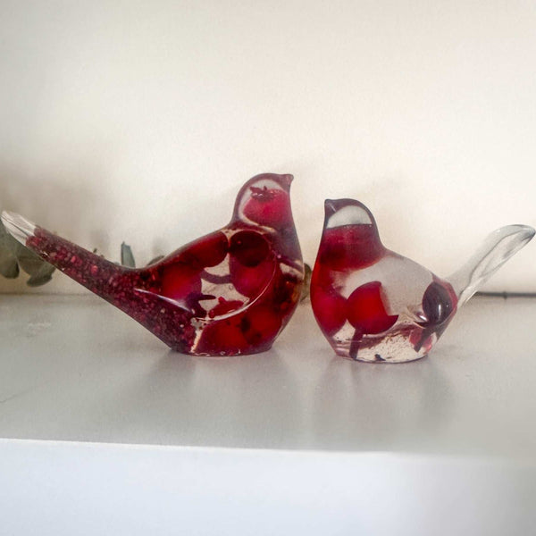 Close-up of glossy red berries suspended in clear hand-poured resin bird with red glitter shimmer