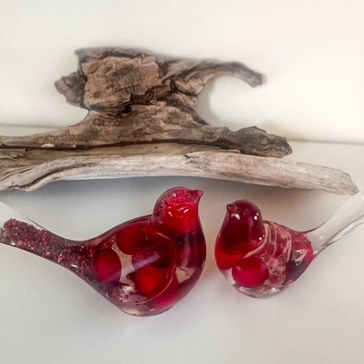 Close-up of glossy red berries suspended in clear hand-poured resin bird with red glitter shimmer