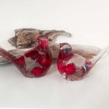 Close-up of glossy red berries suspended in clear hand-poured resin bird with red glitter shimmer
