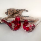 Close-up of glossy red berries suspended in clear hand-poured resin bird with red glitter shimmer