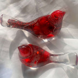 Close-up of glossy red berries suspended in clear hand-poured resin bird with red glitter shimmer