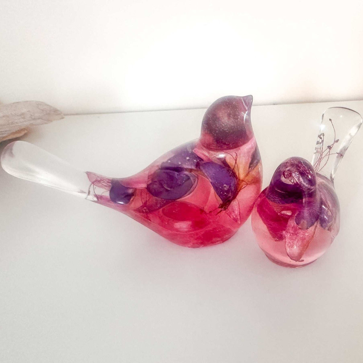 Close-up of real dried fuchsia flowers suspended in deep pink and purple hand-poured resin bird