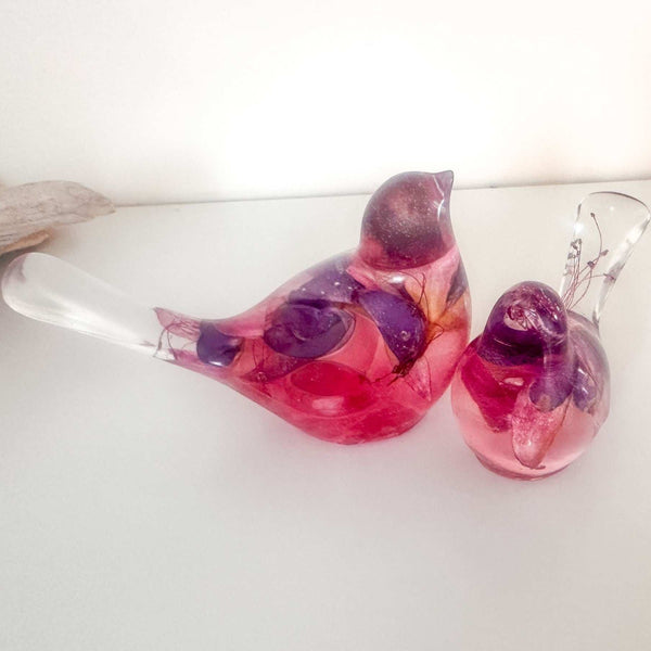Close-up of real dried fuchsia flowers suspended in deep pink and purple hand-poured resin bird