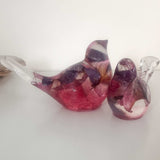 Close-up of real dried fuchsia flowers suspended in deep pink and purple hand-poured resin bird