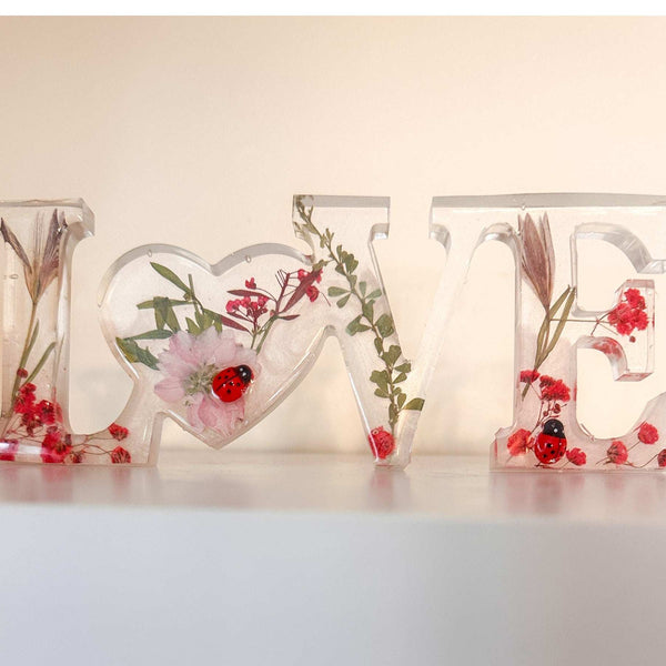 Close-up of real foraged garden greenery and red ladybug charms in resin