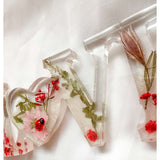 Close-up of real foraged garden greenery and red ladybug charms in resin