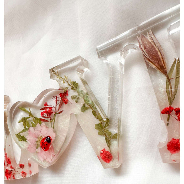 Close-up of real foraged garden greenery and red ladybug charms in resin